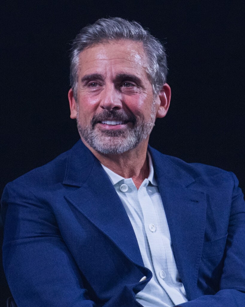 Steve Carell in present day wearing navy suit and light blue dress shirt